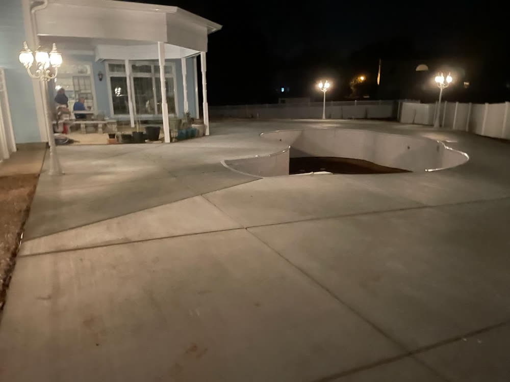 Lamp posts lighting a pool deck and covered patio at night