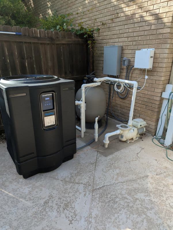 Pool heat pump, filter and pump wired to an outdoor disconnect and weatherproof panel on a brick wall